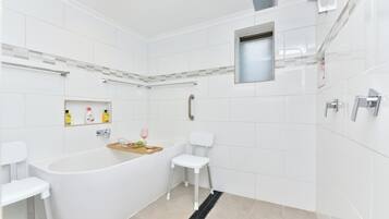 Un baño moderno con una bañera independiente, un inodoro blanco y una zona de ducha.