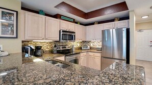 A kitchen with granite countertops, stainless steel appliances, and light-colored cabinets.