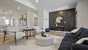 Ein modernes Wohnzimmer mit einer Couch, einem runden Couchtisch und einem Essbereich mit Stühlen und einem Tisch.