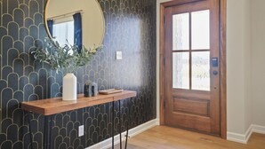 Ein Flur mit Holztür, Spiegel und Ablage mit Vase und Pflanze.