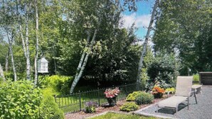 Un jardin avec une clôture, diverses plantes et un banc.