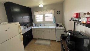 Una cocina compacta con refrigerador, estufa, pileta y cafetera.