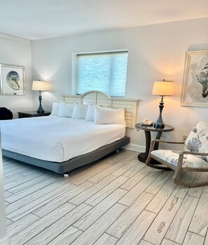 Habitación de hotel impecable con una cama grande, dos lámparas de noche, una mesita redonda y una silla.