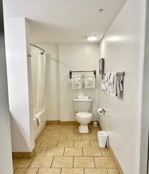Un baño pequeño y limpio con inodoro, cortina de ducha, toallero y un cesto de basura.