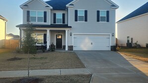 A two-story house with a garage, a front porch, and a small tree in the yard. - Charming house just minutes to the Augusta National in fabulous North Augusta (North Augusta)