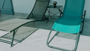 A room with a teal lounge chair, a small table with a decorative item, and a window with blue shutters. - Villa tempÔ In a quiet, secure residence. Close to the beach and port (Sainte-Rose)