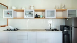A modern kitchen with white cabinets, a stainless steel refrigerator, a built-in oven, and a coffee machine. - Elephant Villa 5 by Villa Finder (Ubud)