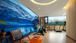 A modern hotel room with a large mural of a mountainous landscape, a treadmill, and exercise equipment. - lanziguojijiudian (Chongqing)