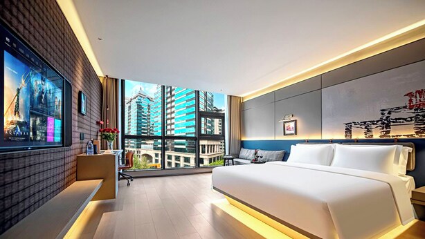 A modern hotel room with a large bed, a desk, and a TV mounted on the wall. - lanziguojijiudian (Chongqing)