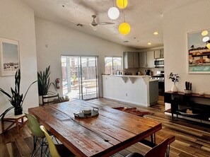 A spacious kitchen with a central island, a dining area with a wooden table, and a living area with a sofa and a coffee table. - Charming 3-bedroom house with Pool/Jacuzzi and Desert Mountain View (Desert Hot Springs)