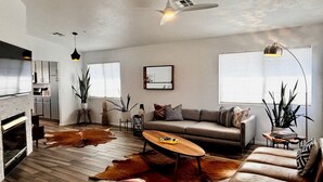 A modern living room with a sofa, coffee table, and a fireplace. - Charming 3-bedroom house with Pool/Jacuzzi and Desert Mountain View (Desert Hot Springs)