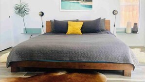 A modern bedroom with a large bed, a view of the sea, and a minimalist decor. - Charming 3-bedroom house with Pool/Jacuzzi and Desert Mountain View (Desert Hot Springs)