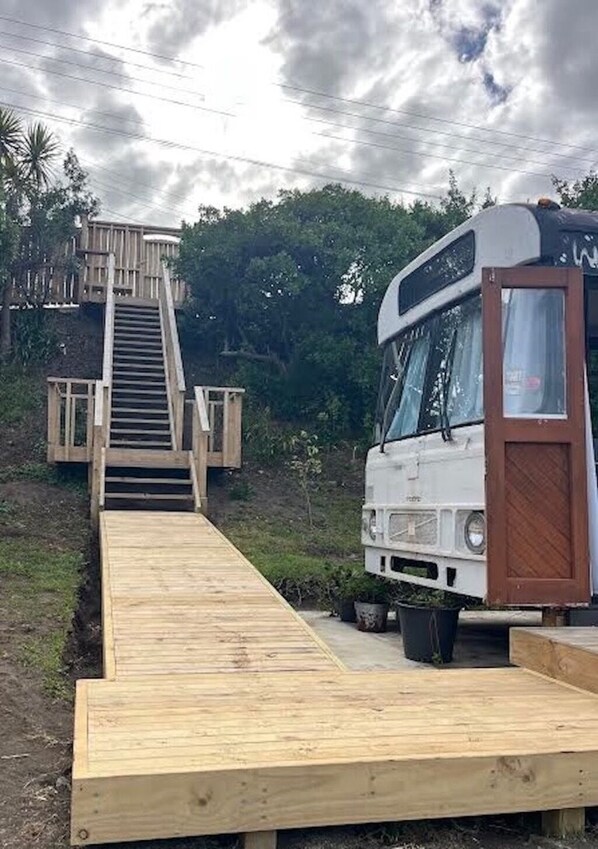 A bus parked on a wooden ramp leading to a wooden deck. - Luxury Beach Bus (Whanganui)