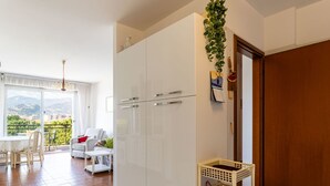 En moderne stue med en hvid sofa, et spisebord og udsigt til det fri.