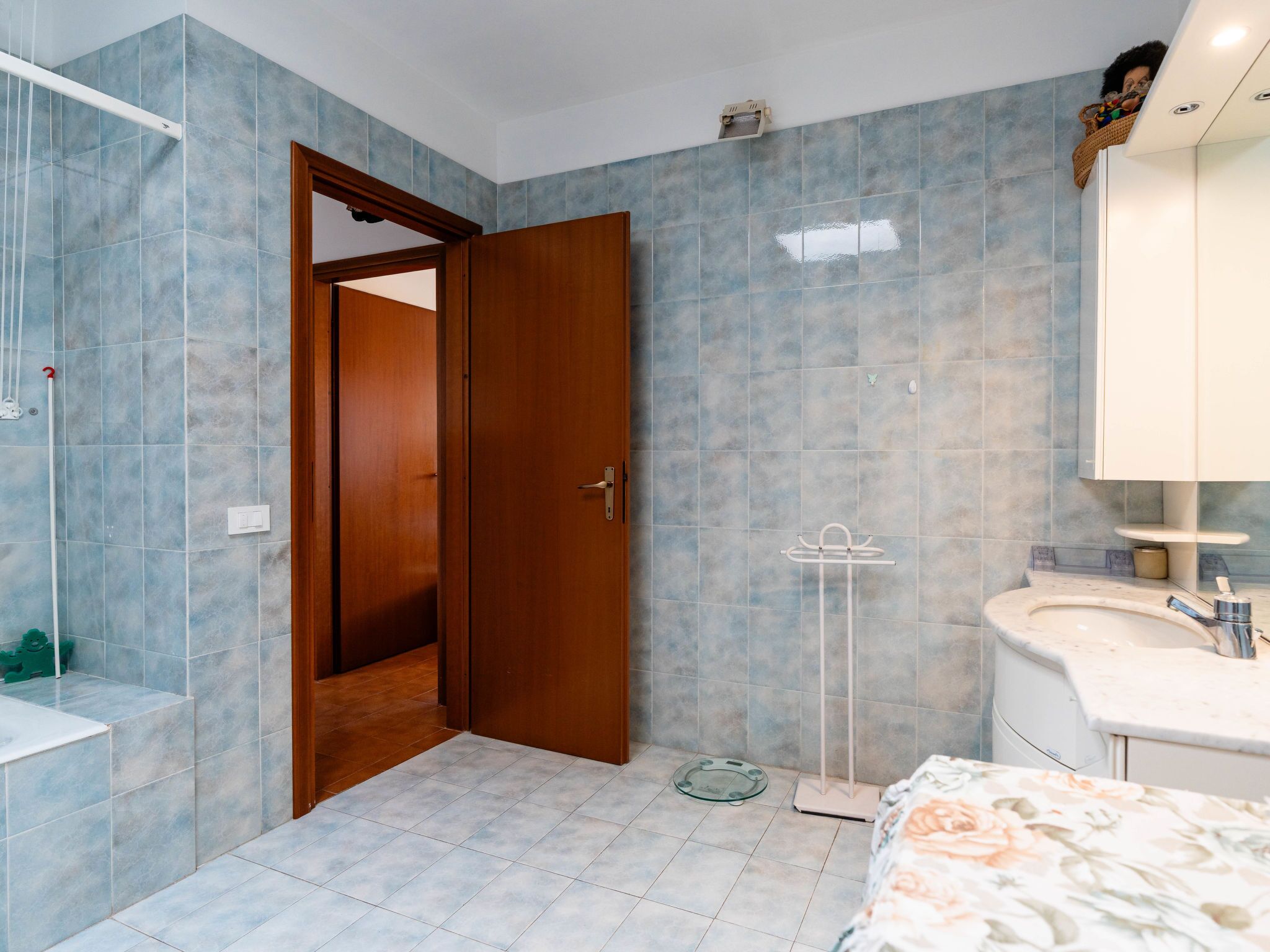 A bathroom with a wooden door, a white sink, and a mirror.
