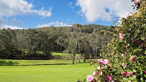 A lush green field with a forested hill in the background. - Mount Lofty Golf Course (Stirling)