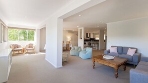 A spacious living room with a large window, a sofa, a coffee table, and two chairs. - Mount Lofty Golf Course (Stirling)