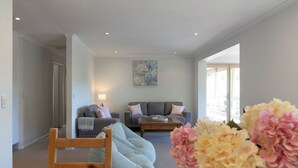 A modern living room with a grey sofa, a wooden chair, and a coffee table. - Mount Lofty Golf Course (Stirling)