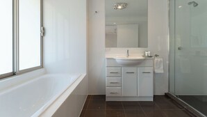 A modern bathroom with a bathtub, a sink, and a glass shower enclosure.