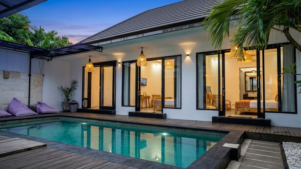 Une maison moderne dotée d’une piscine, de grandes fenêtres et d’un intérieur bien éclairé.