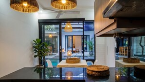 Un espace repas moderne avec une table en verre, des paniers en osier et une vue sur l’espace extérieur.