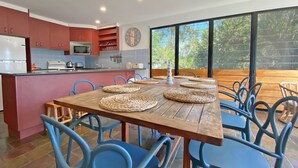 Eine moderne Küche mit roten Schränken, einer Mikrowelle und einem Essbereich mit einem Holztisch und blauen Stühlen.