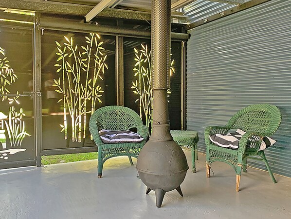 Un'area patio con due poltrone in vimini, un grande fornello e decorazioni murali in bambù.