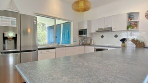 A modern kitchen with a granite countertop, stainless steel appliances, and white cabinetry.