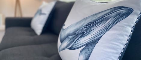 A sofa with three cushions featuring a whale design.