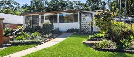 A house with a covered patio, a well-maintained lawn, and a variety of plants.