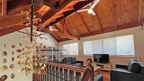 Een houten interieur met stapelbedden, een televisie en een trap met een leuning.