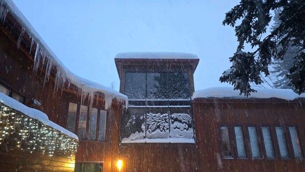 Ein Gebäude mit großem Fenster, Holzfassade und Schneebedeckung.