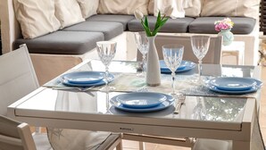 A dining table set with blue plates, clear glassware, and a vase with white flowers.