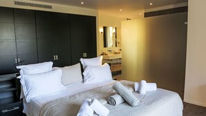 A modern hotel room with a large bed, dark wooden wardrobe, and a bathroom with a mirror and sink. - La Cupulatta by Interhome (Sainte Lucie Porto Vecchio)