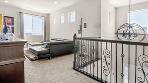 Un salón espacioso con un sofá seccional gris, una mesa de centro de madera y un ventanal que proporciona luz natural.