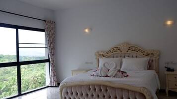 A large bed with a tufted headboard, a nightstand, and a window with curtains.