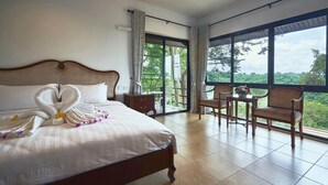 A hotel room with a large bed, a balcony with a table and chairs, and a view of the outdoors. - Channgarm Mountain View Resort  (Sikhio)