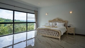 A bedroom with a large window, a bed with a decorative headboard, a bedside table, and a nightstand. - Channgarm Mountain View Resort  (Sikhio)