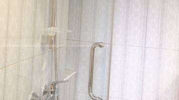A shower area with a handheld showerhead, a handheld shower attachment, and a grab bar.