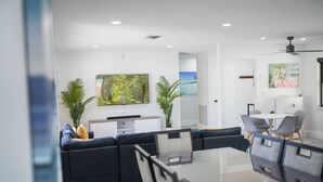 En moderne stue med en hjørnesofa, et spisebord med stole og et køkken i baggrunden.