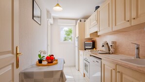 A compact kitchen with a dining table, a microwave, and a sink. - Le Clos Saint Saens by Interhome (Saint Aygulf)