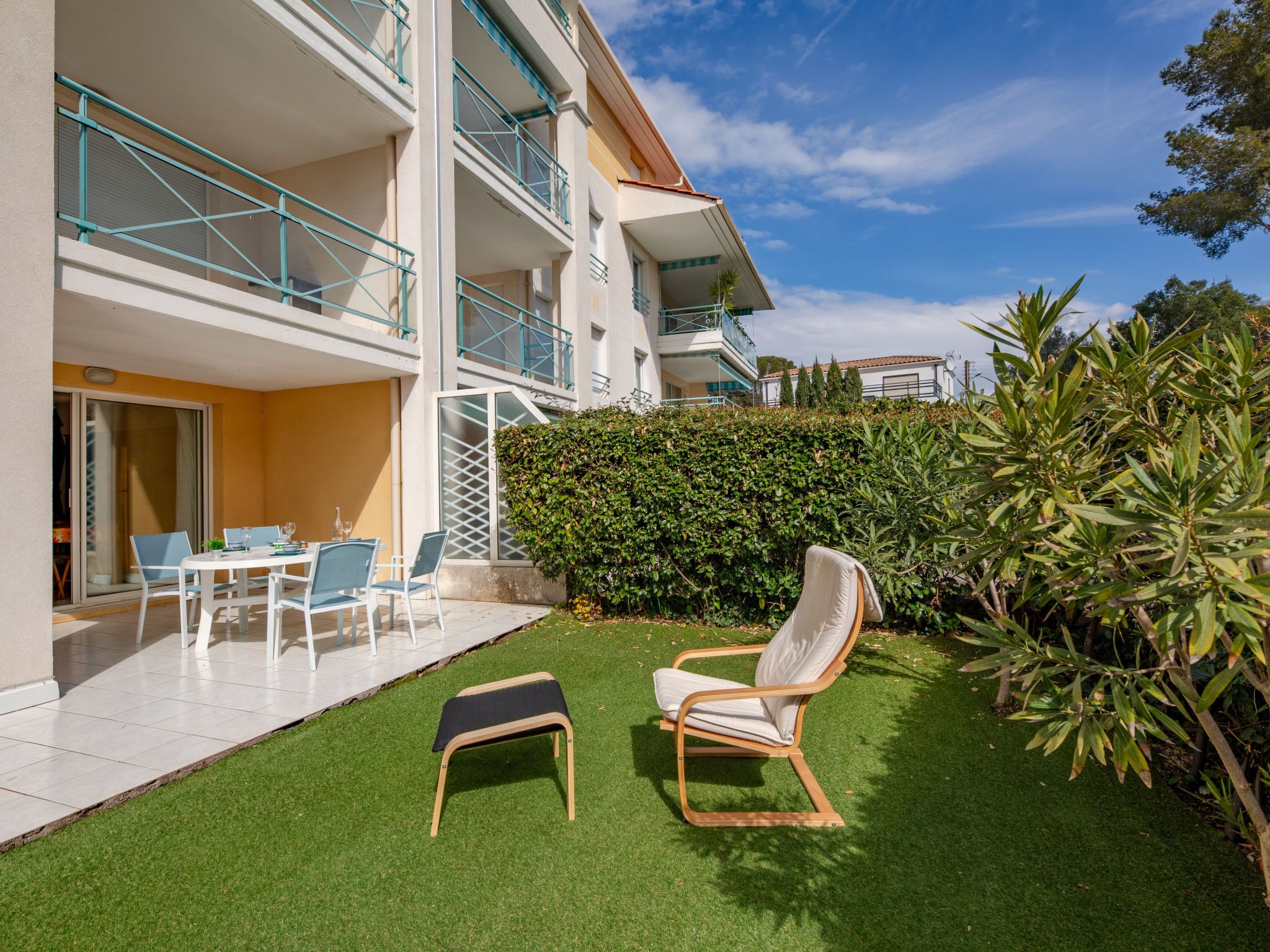 Eine moderne Wohnung mit Balkon, einer kleinen Sitzecke im Freien und einem gepflegten Rasen.