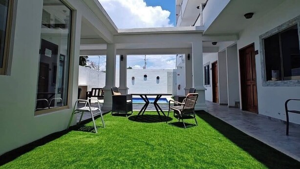 A courtyard with a green lawn, a table, and chairs. - Hotel Yukon (Playa del Carmen)