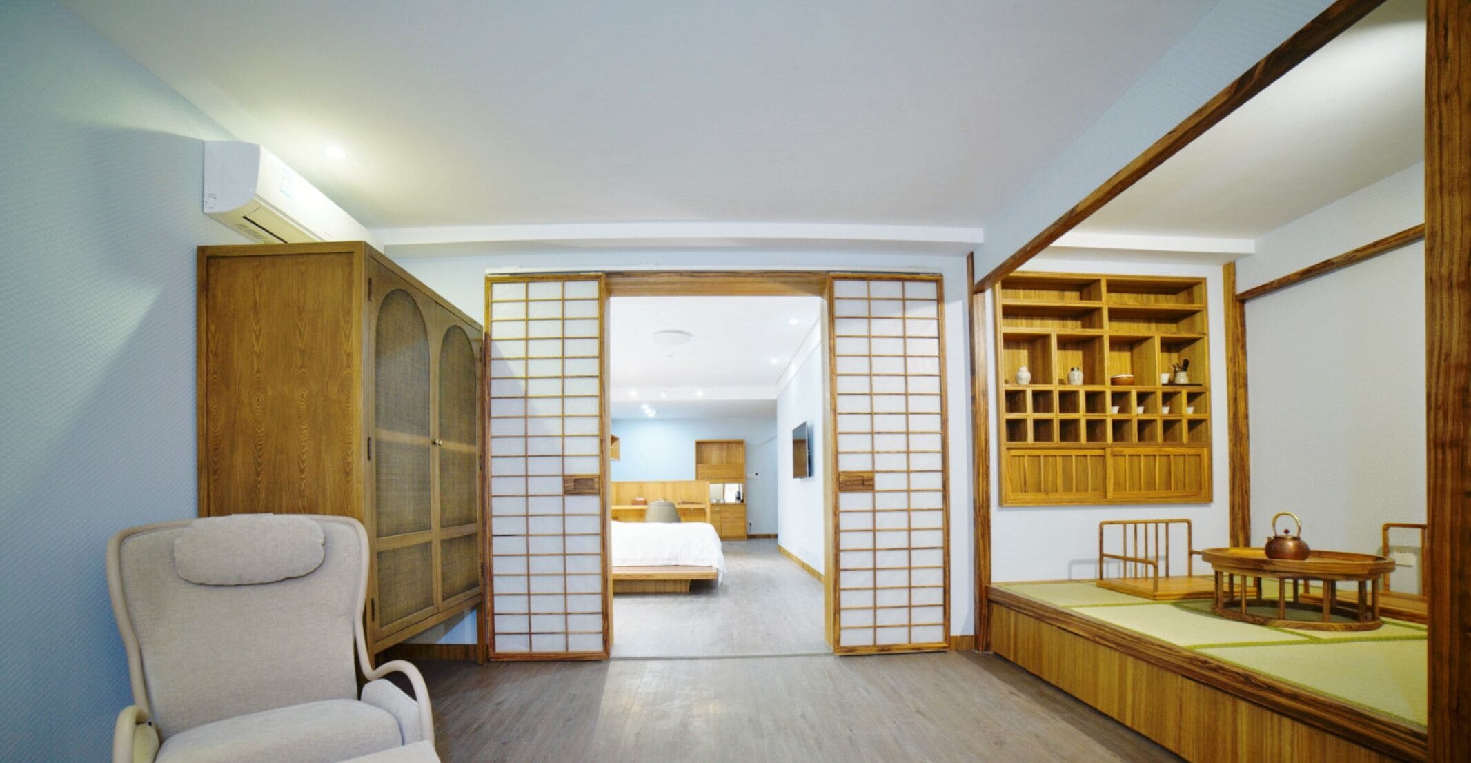 A traditional Japanese-style room with sliding doors, a wooden cabinet, a bed, and a tea set.