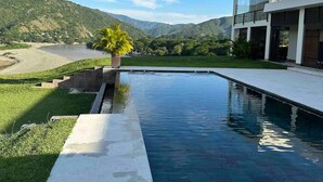 Une maison moderne dotée d’une piscine, d’une pelouse bien entretenue et offrant une vue sur une chaîne de montagnes.
