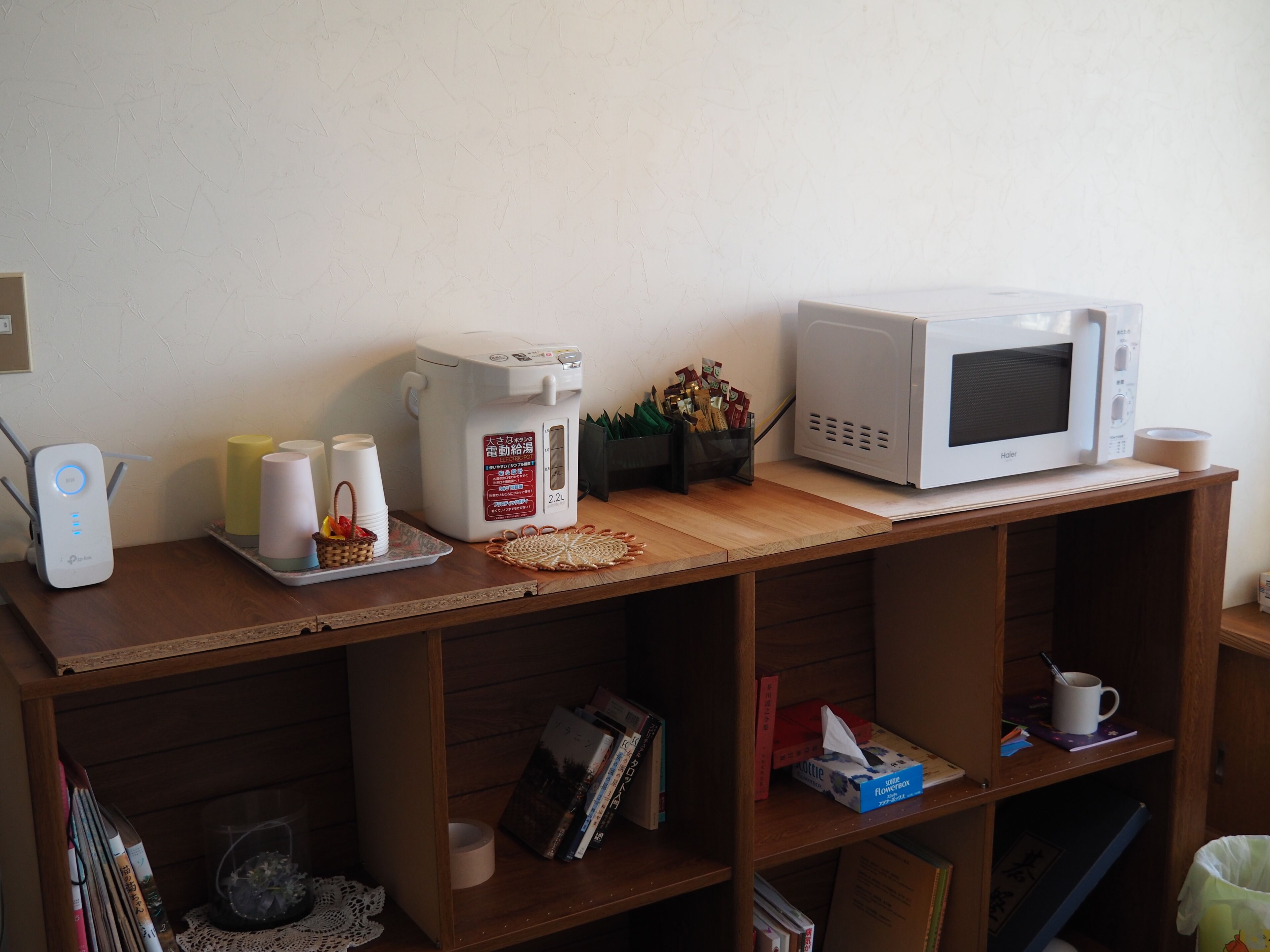 A kitchen area with a microwave, a rice cooker, and a coffee maker on a wooden countertop.