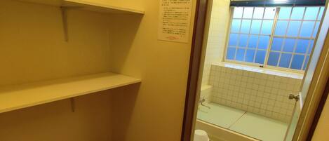 A small bathroom with a toilet, a sink, and a window. There is a sign on the wall with text.