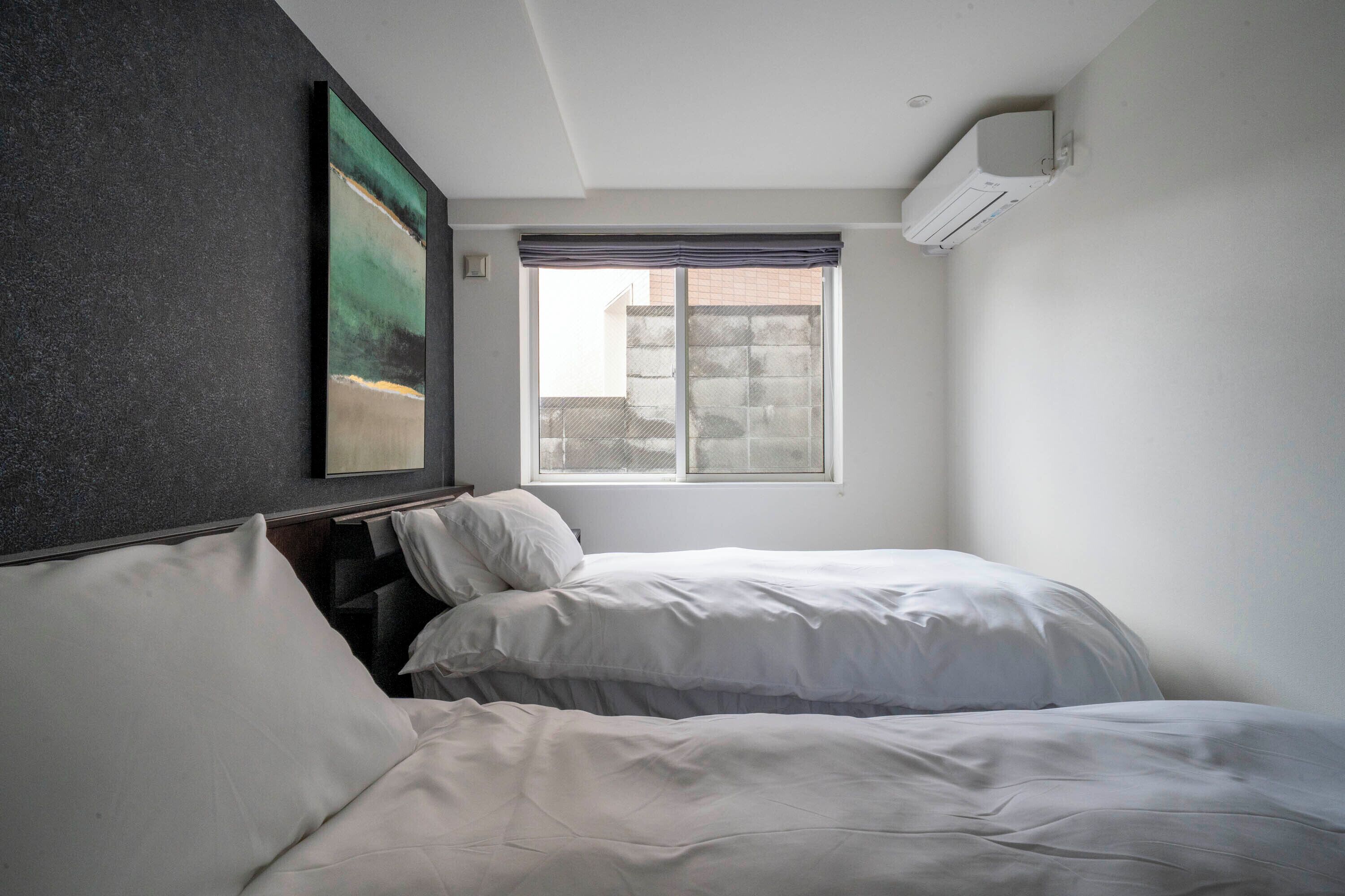 A bedroom with two beds, a window, and an air conditioning unit.