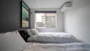 A bedroom with two beds, a window, and an air conditioning unit.