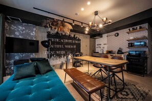 A modern living space with a sofa, bench, dining table, and kitchen area. - TAKETO STAY KOTONI 101 (Sapporo)